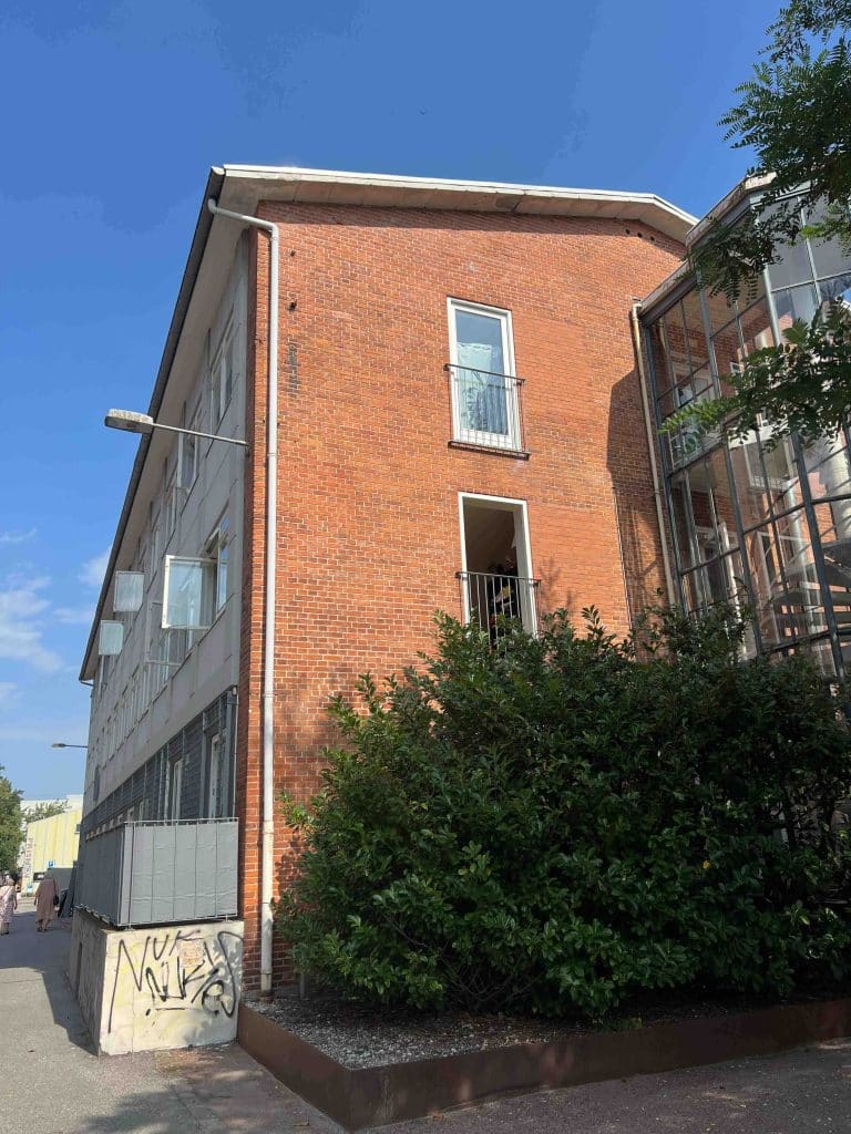 Holmbladsgade 70c – bagfacade med murstensvæg, vinduer og grøn beplantning